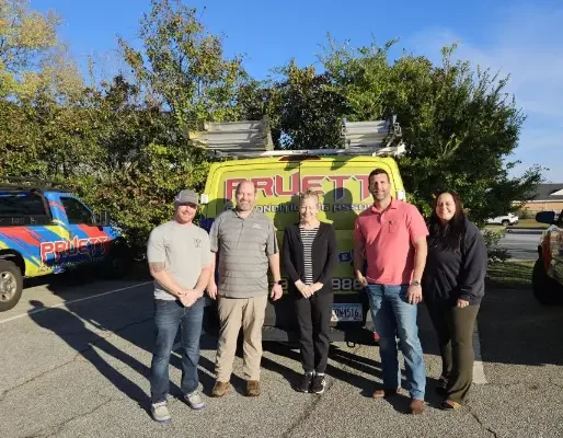 The team at Pruett Air Conditioning smiling together in front of a service van The team at Pruett Air Conditioning smiling together in front of a service van