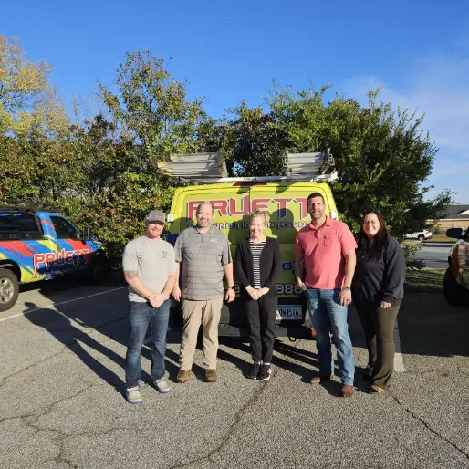 The team at Pruett Air Conditioning smiling together in front of a service van